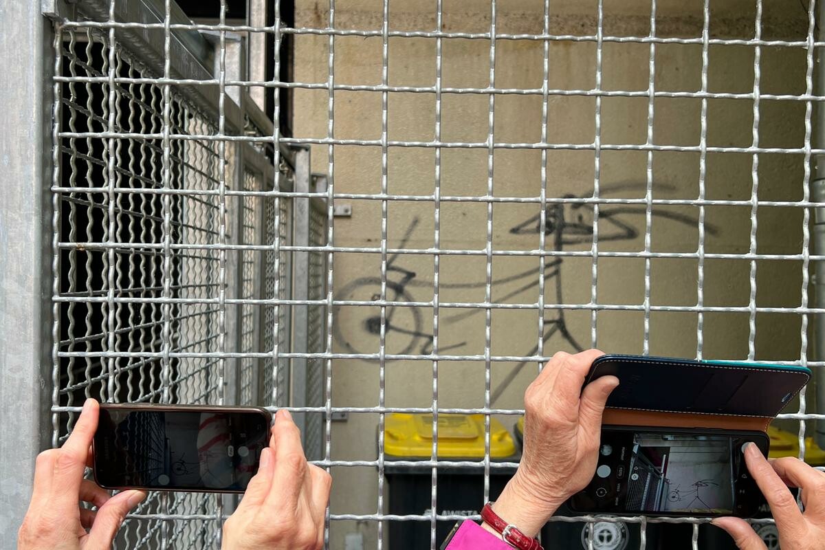 Zwei Personen fotografieren mit ihren Handys ein Naegli-Graffiti