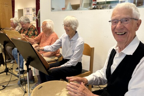 Eine Gruppe von älteren Leuten, die auf Stühlen sitzen und Musik machen