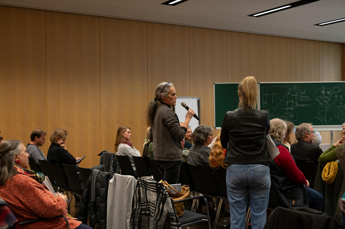 Eine Frau, die vor einer Gruppe von Menschen in ein Mikrofon spricht